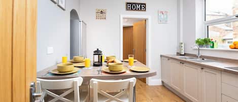 Una cocina moderna con una mesa de comedor preparada para el desayuno, un menú de café y un cartel con la palabra 'HOME' en la pared.