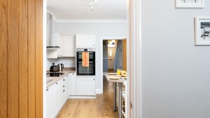A compact kitchen with white cabinets, a built-in oven, and a dining area with a table and chairs. - 38 Ashville Avenue (Scarborough)