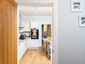 A compact kitchen with white cabinets, a built-in oven, and a dining area with a table and chairs. - 38 Ashville Avenue (Scarborough)