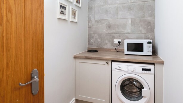 A compact laundry room with a washing machine, a microwave, and a small cabinet. - 38 Ashville Avenue (Scarborough)