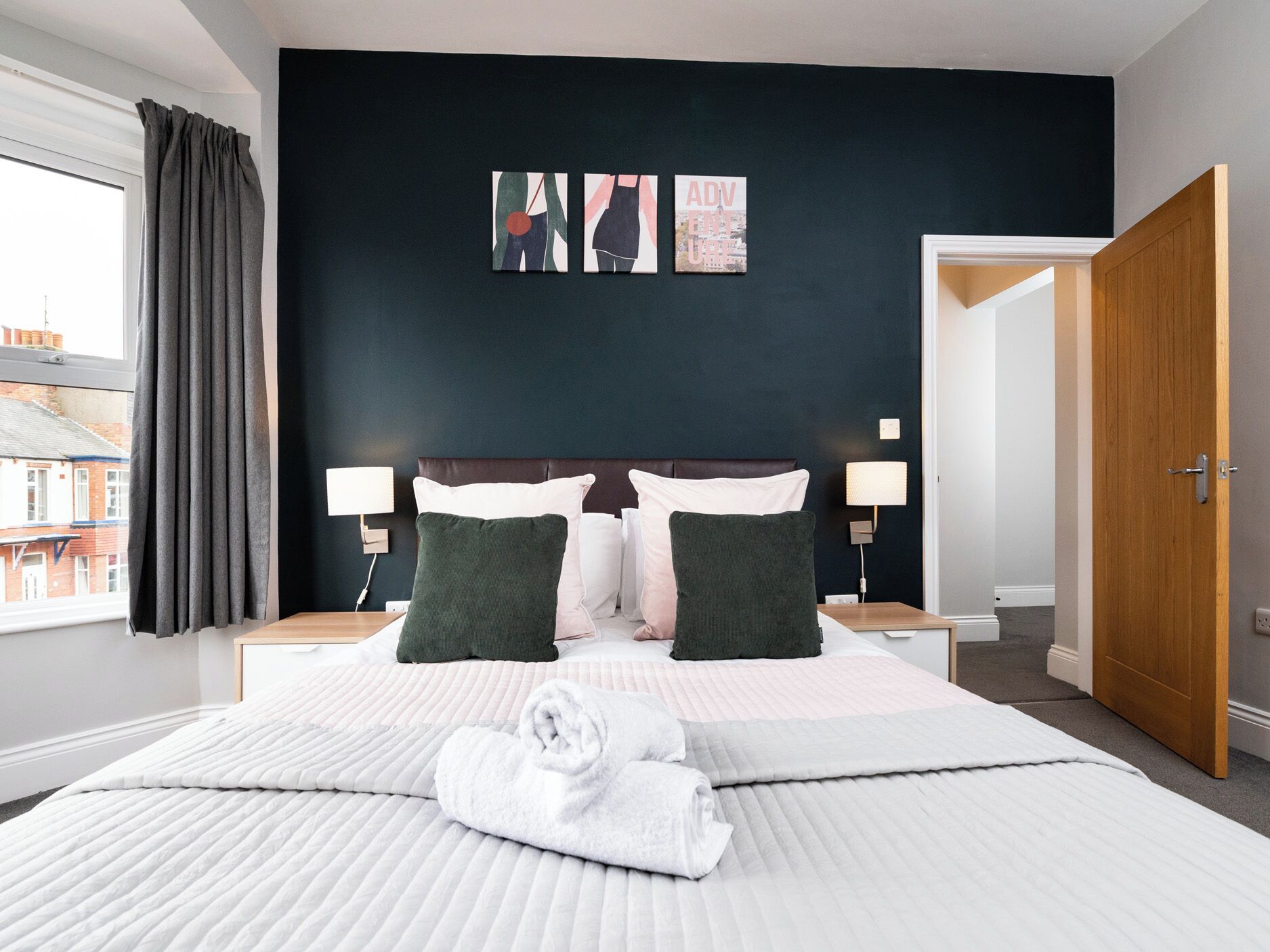 Ein Hotelzimmer mit einem großen Bett, zwei Nachttischen, einem Schrank und einem Fenster mit Vorhängen.