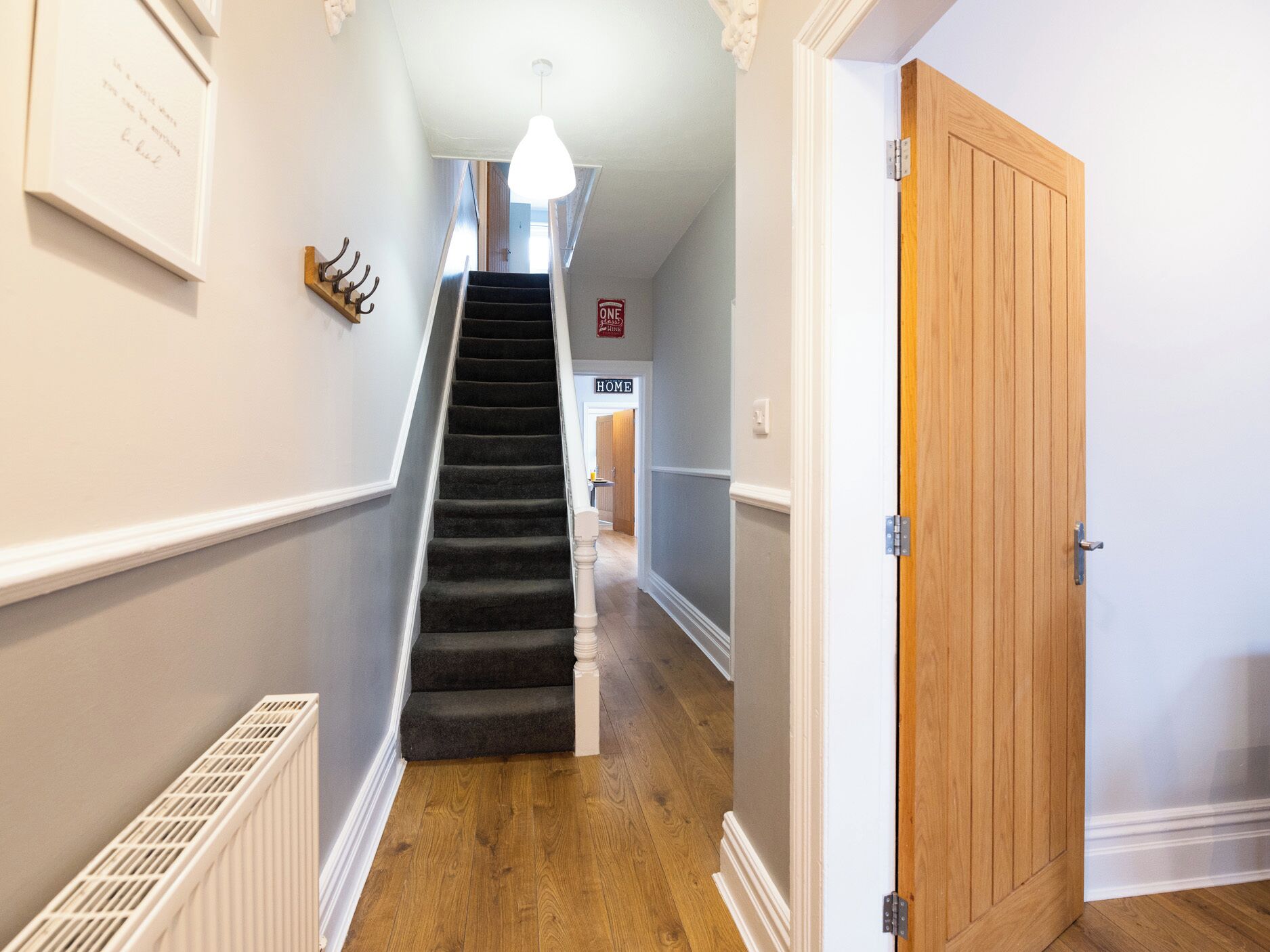 A staircase leading to a room with a wooden door, a radiator, and a sign indicating a one-way home.