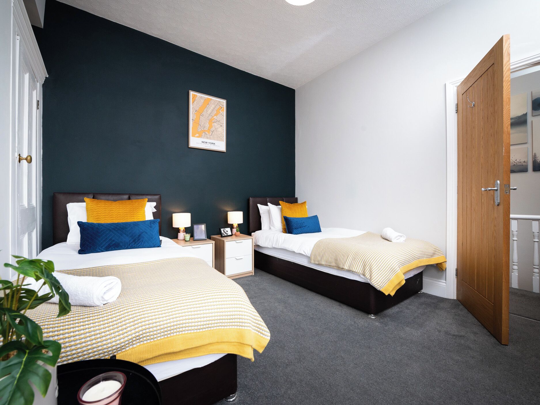 Une chambre d’hôtel avec deux lits, une carte accrochée au mur et une porte donnant sur un balcon.