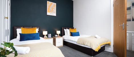 Une chambre d’hôtel avec deux lits, une carte accrochée au mur et une porte donnant sur un balcon.