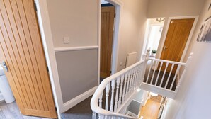 A staircase with a white handrail leading to a landing, a wooden door, and a carpeted floor. - 38 Ashville Avenue (Scarborough)