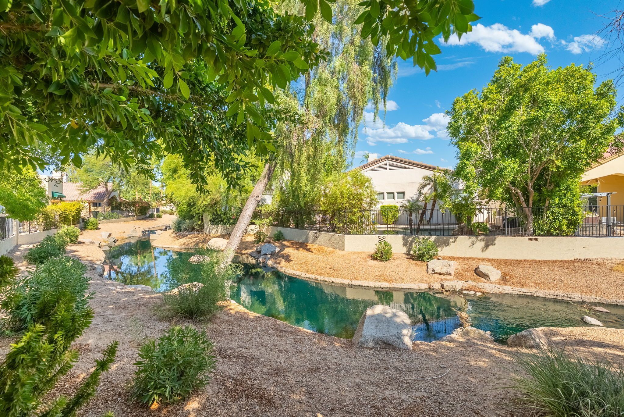 A residential area with a swimming pool, surrounded by trees and a fence.