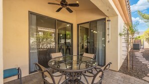 A glass-enclosed patio with a round table and chairs, a ceiling fan, and a view of the outdoors. - Midterm Retreat in Gated Golf Community (Litchfield Park)