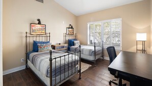 A bedroom with two beds, a ceiling fan, a window with blinds, and a desk with a chair. - Midterm Retreat in Gated Golf Community (Litchfield Park)