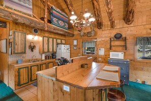 A rustic wooden interior with a central island, wooden cabinets, a chandelier, and a window with a view. - 2 Elks Cabin with Private Hot Tub | Ski Wolf Creek (South Fork)