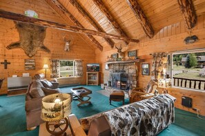 A log cabin interior with a fireplace, leather furniture, and mounted animal heads. - 2 Elks Cabin with Private Hot Tub | Ski Wolf Creek (South Fork)