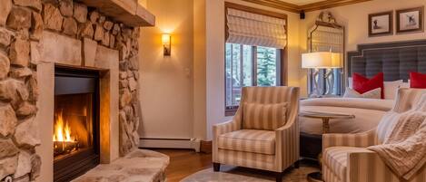 A cozy living room with a stone fireplace, comfortable seating, and a chandelier.