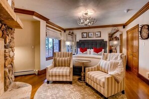 A cozy bedroom with a bed, two armchairs, a round table, and a stone wall. - BC Slopeside Ski Studio, Hot Tub, Resort Amenities (Beaver Creek)