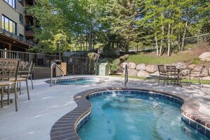 A swimming pool with a brick border, surrounded by outdoor seating and a fence. - BC Slopeside Ski Studio, Hot Tub, Resort Amenities (Beaver Creek)