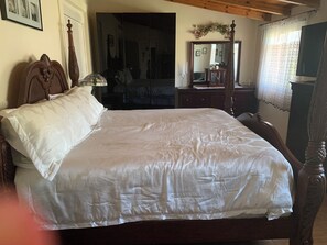 A bedroom with a large bed, a wooden headboard, a dresser, a mirror, and a window with curtains. - Escape to our spacious country home. (DIMOS EUROTA)