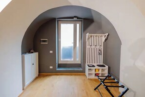 A room with a sloped ceiling, a door leading to a balcony, a small table with a chair, and a wooden floor. - Lavika Home (Catania)