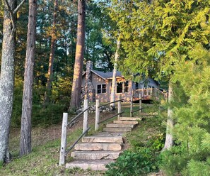 A cabin with a stone staircase leading to a wooden deck. - Waterfront Minocqua Retreat with Lake Views (Minocqua)