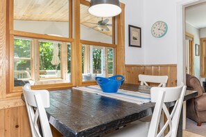 A dining area with a black table, white chairs, a blue bowl, and a clock on the wall. - Waterfront Minocqua Retreat with Lake Views (Minocqua)