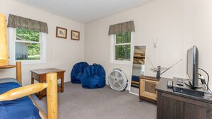 Una habitación con cama, escritorio, silla, ventilador y televisor.