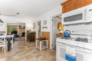 A kitchen with a stove, a kettle, and a dining area with a table and chairs. - Waterfront Minocqua Retreat with Lake Views (Minocqua)