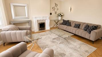 A spacious living room with a fireplace, a sofa set, and a chandelier.
