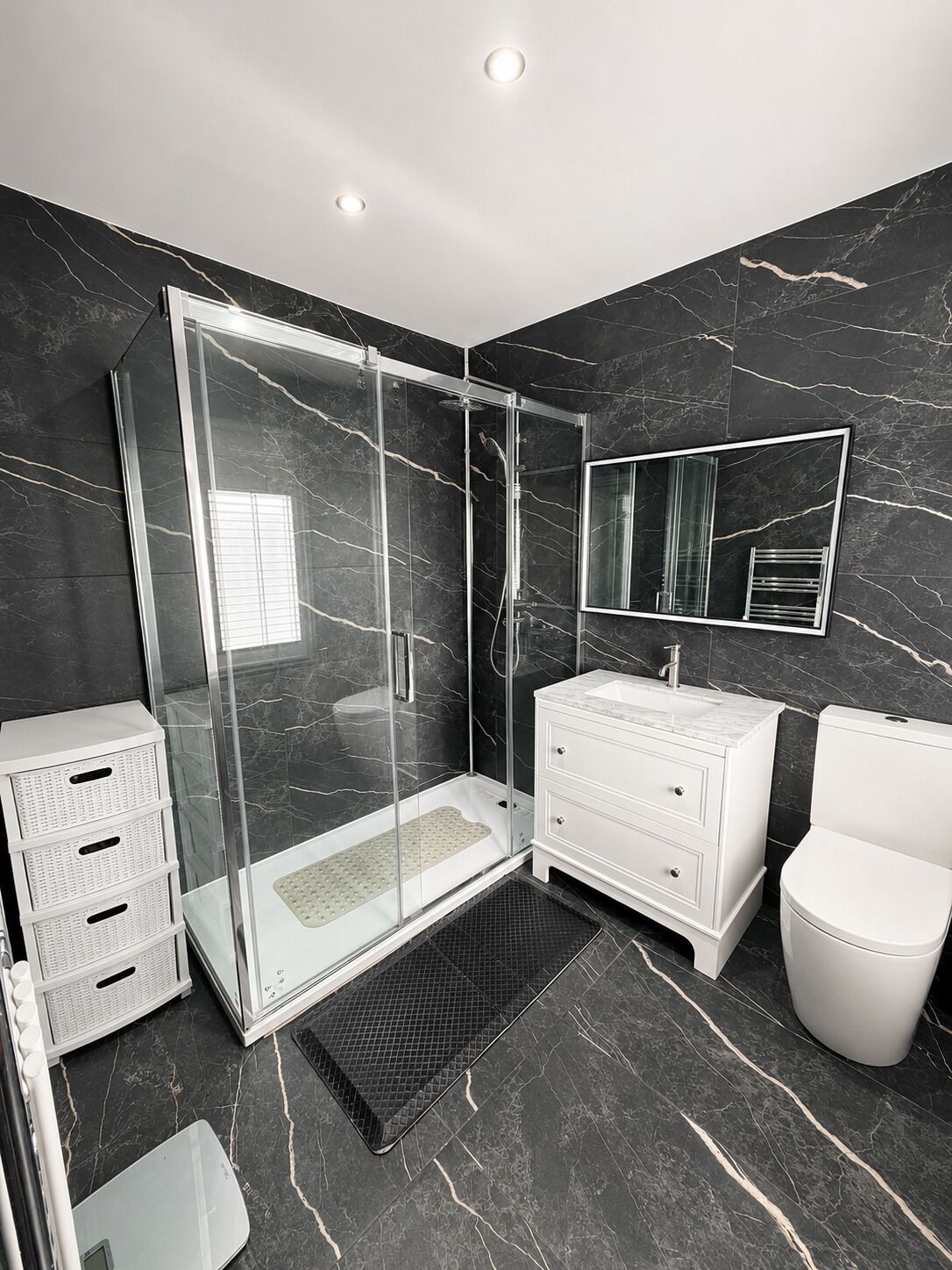 A modern bathroom with a glass-enclosed shower, white vanity, and a toilet.