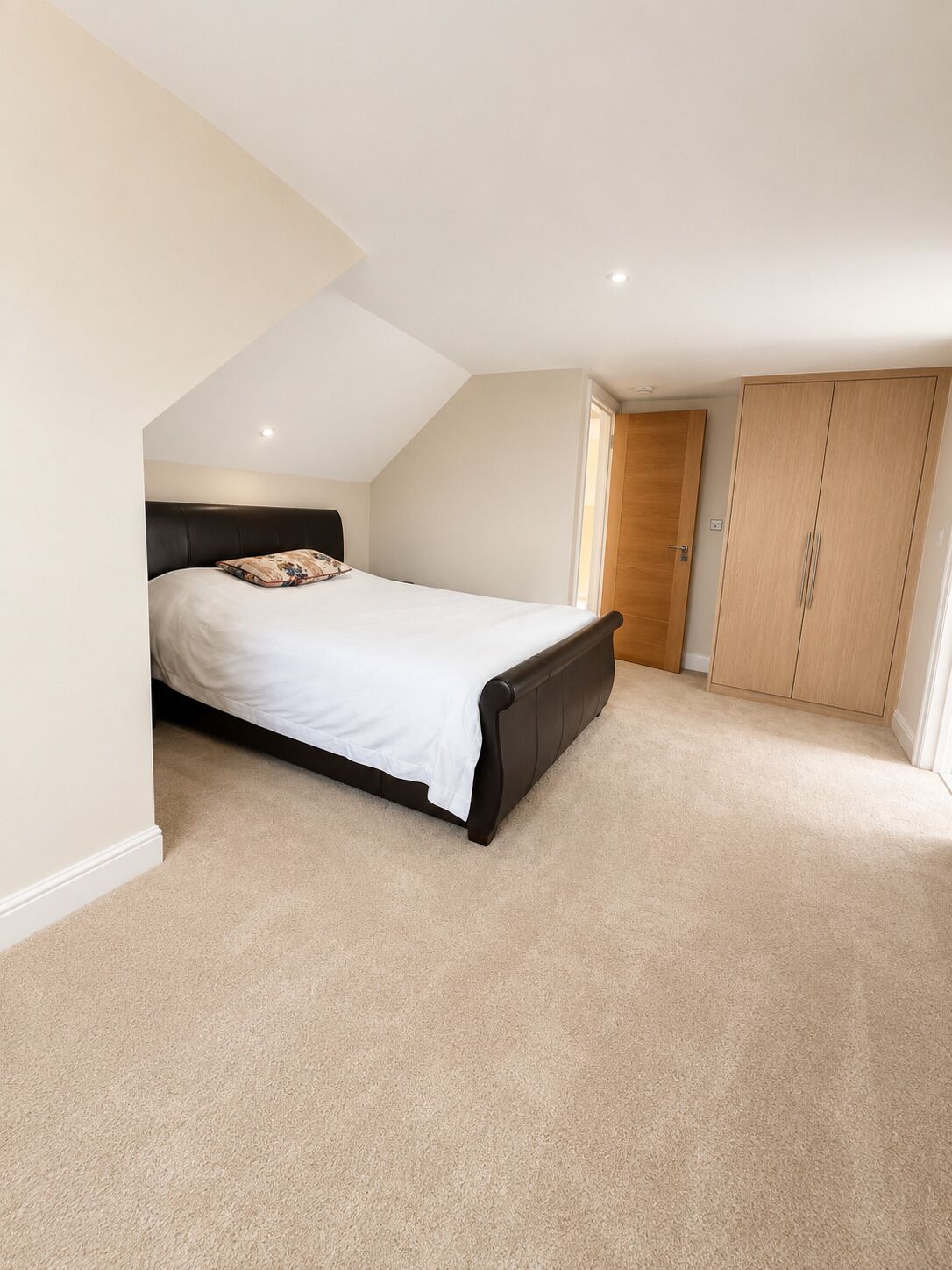 A bedroom with a bed, a wardrobe, and a sloped ceiling.