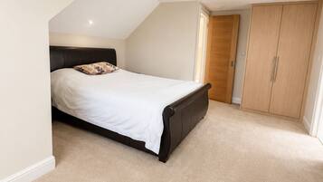 A bedroom with a bed, a wardrobe, and a sloped ceiling.