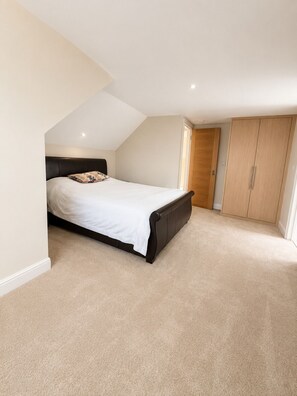 Ein Schlafzimmer mit Bett, Schrank und schrägverdeckter Decke.
