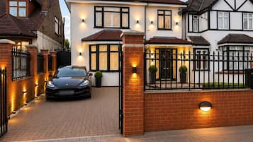 A residential property with a paved driveway, a gated entrance, and a parked car.