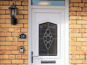 A white door with a glass panel, a number plate, a doorbell, and a wall-mounted light fixture. - 18 Mayville Avenue (Scarborough)
