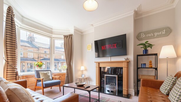 Una sala de estar con chimenea, un televisor montado encima y un sofá.