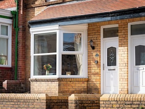 A two-story house with a brick facade, a white front door with a glass panel, and a window with a flower vase. - 18 Mayville Avenue (Scarborough)