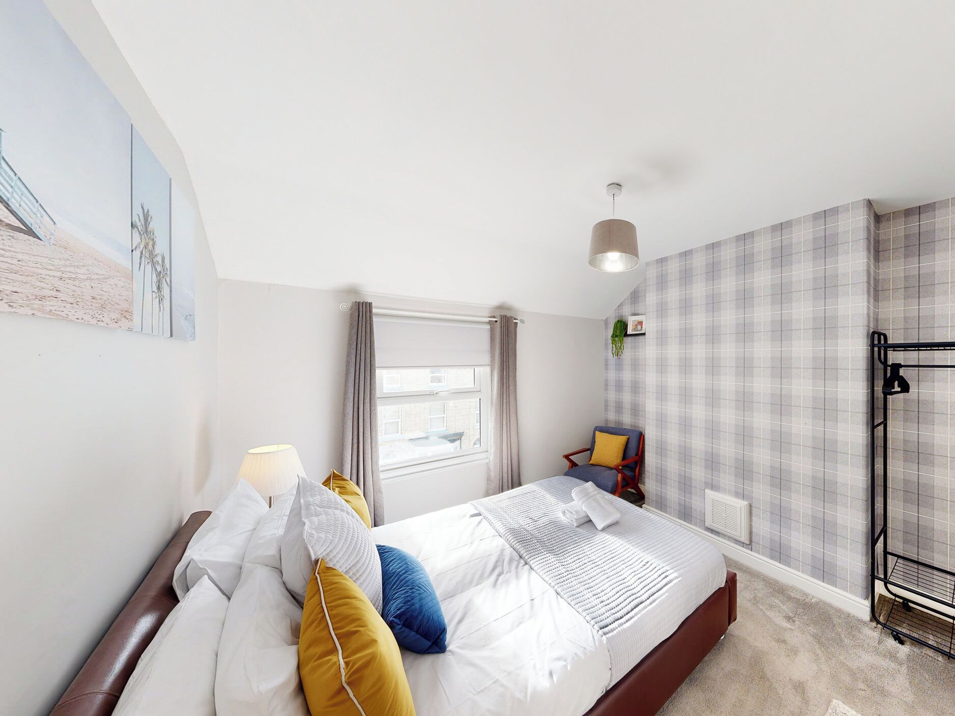 Une chambre d’hôtel avec un lit, une fenêtre, une chaise et un radiateur.