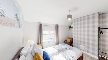 A hotel room with a bed, a window, a chair, and a radiator.