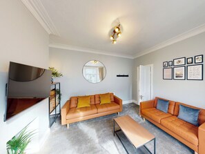 A living room with two sofas, a coffee table, a TV, a mirror, and framed pictures on the wall. - 44 Norwood Street (Scarborough)