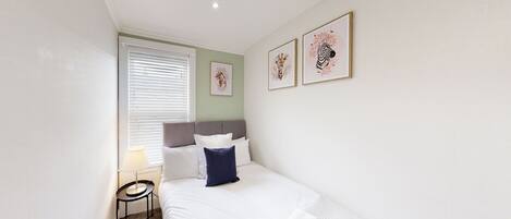 A hotel room with a bed, a bedside table, a lamp, and artwork on the wall.