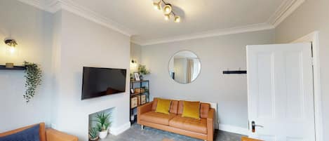 A living room with a flat-screen TV, a sofa set, a coffee table, and a fireplace.