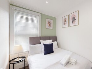 A bedroom with a bed, a nightstand, a lamp, and two framed pictures on the wall. - 44 Norwood Street (Scarborough)