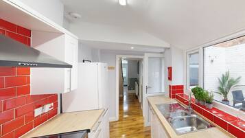 Una cocina moderna con baldosas rojas y blancas, electrodomésticos de acero inoxidable y encimera de madera.