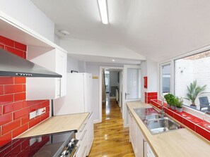 A modern kitchen with red and white tiles, stainless steel appliances, and a wooden countertop. - 44 Norwood Street (Scarborough)