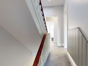 A clean, narrow hallway with a wooden staircase on one side and a grey wall on the other. - 44 Norwood Street (Scarborough)