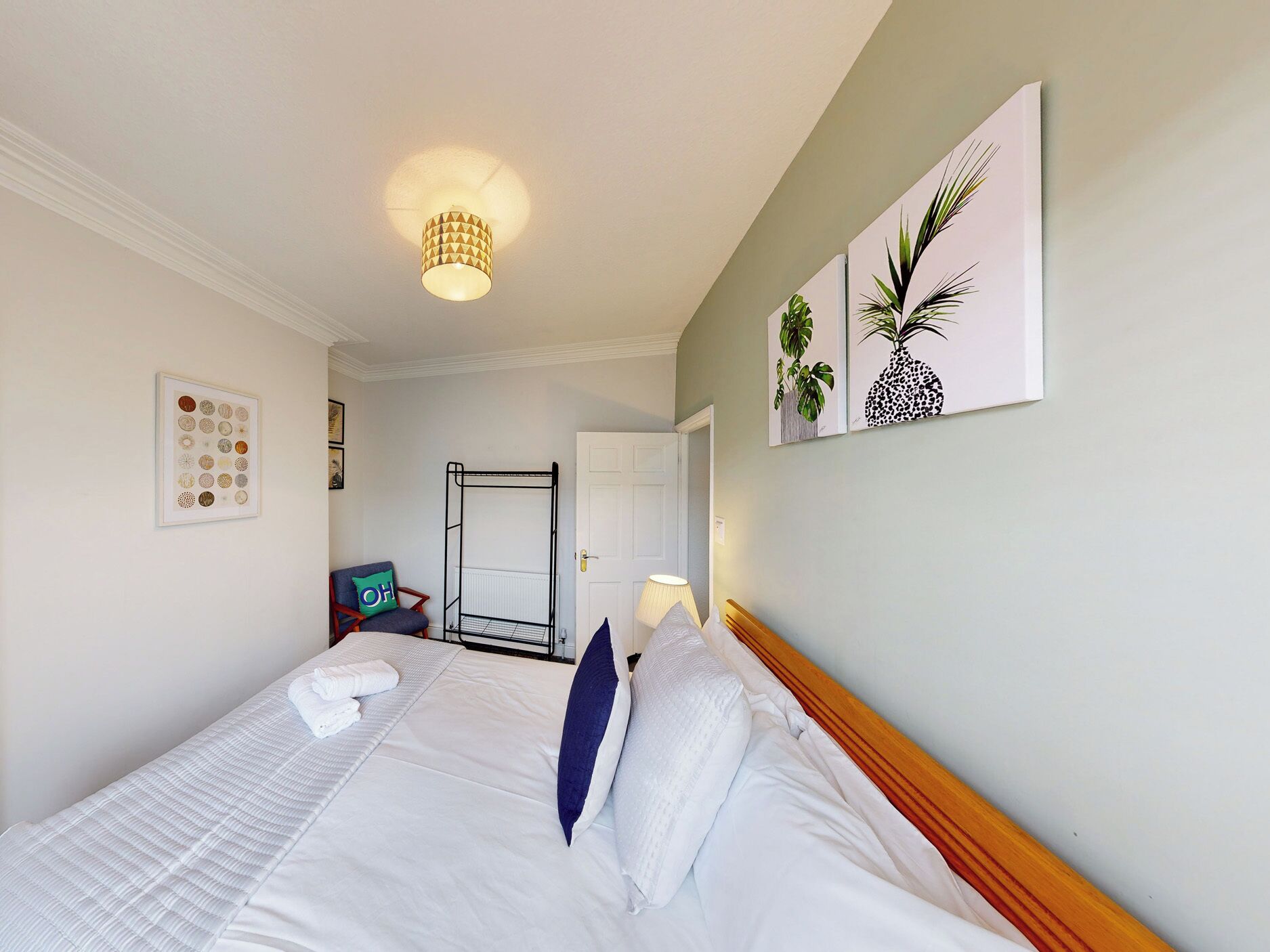 A hotel room with a bed, a chair, a radiator, and artwork on the wall.