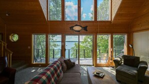 A cabin interior with a large windowed front door, a sofa, a coffee table, and a fish hanging on the wall. - Edgewater Haven on Lake Chetac (Birchwood)