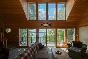 Ein Ferienhaus-Interieur mit großer Eingangstür mit Fenstern, einer Couch, einem Couchtisch und einem Fisch an der Wand.