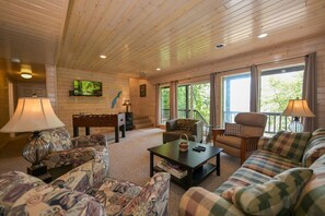 A cozy living room with a sofa, armchairs, a coffee table, and a foosball table. - Edgewater Haven on Lake Chetac (Birchwood)