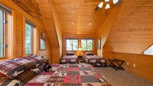 A cabin with two bedrooms, each with a bed and a nightstand, a window, and a ceiling fan. - Edgewater Haven on Lake Chetac (Birchwood)