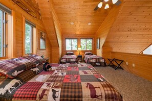 Eine Hütte mit zwei Schlafzimmern, jeweils mit einem Bett, einem Nachttisch, einem Fenster und einem Deckenventilator.