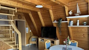 Ein Holzinterieur mit einem Esstisch, Stühlen, einem Fernseher und einer Treppe.