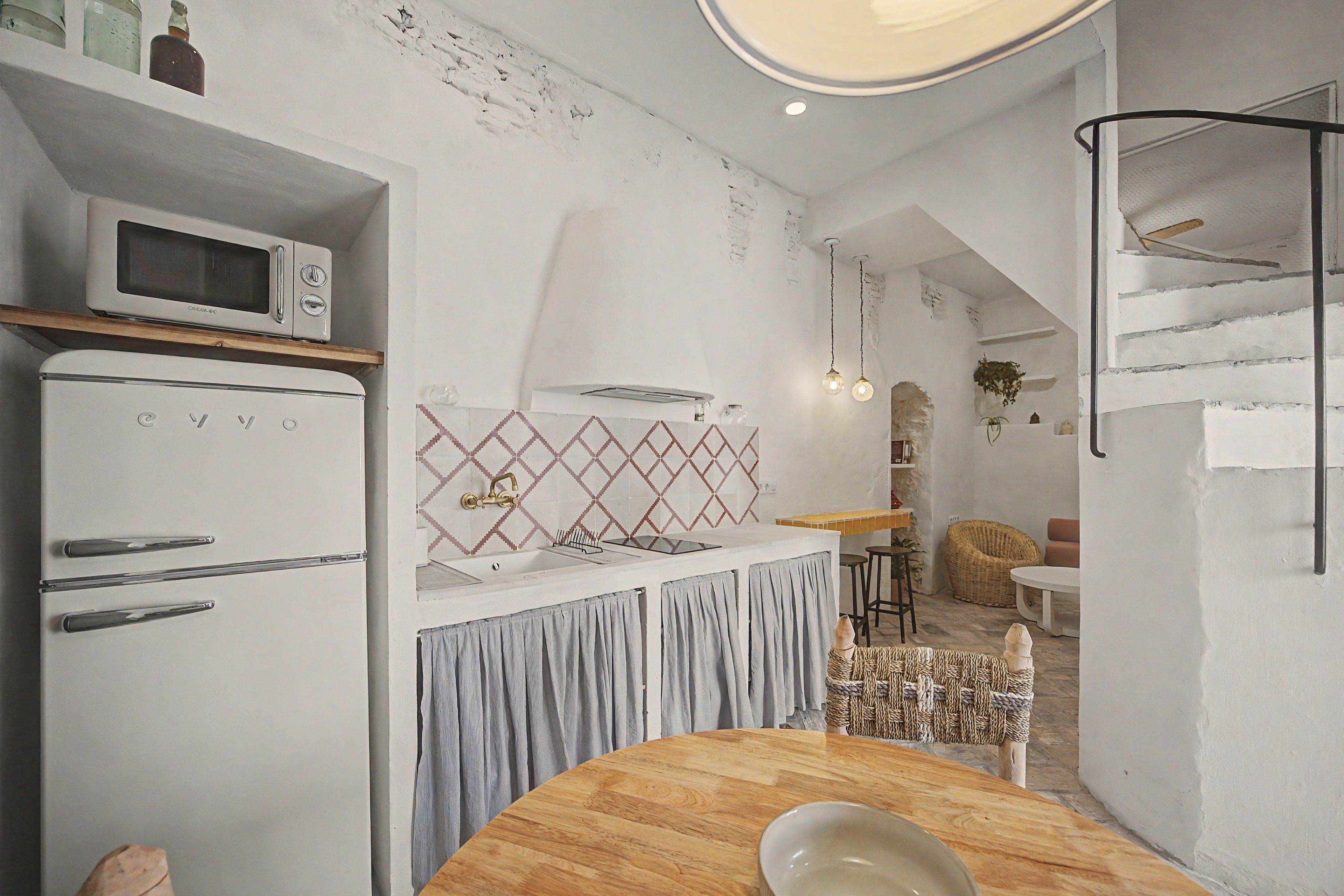 Cocina compacta con microondas, un lavamanos y una mesa de comedor redonda.