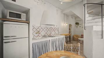 Cocina compacta con microondas, un lavamanos y una mesa de comedor redonda.